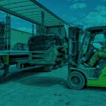 Countrystyle image of fork truck loading bails onto truck.